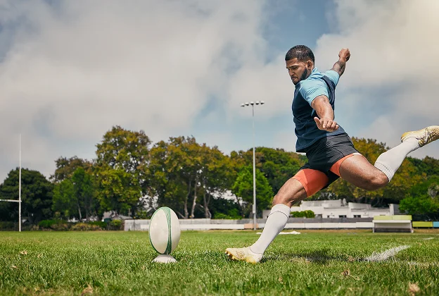 Joueur de rugby musclé donnant un coup de pied à un ballon sur le terrain à Salbris en Loir-et-Cher 41