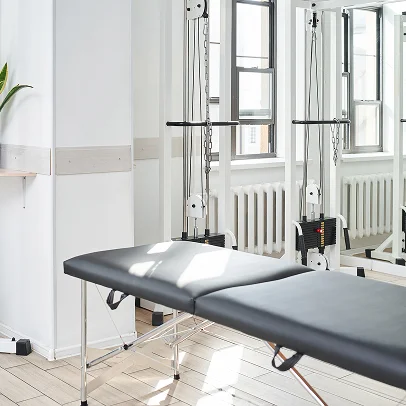 Table de massage dans une salle de rééducation avec appareils de musculation et grandes fenêtres à Salbris en Loir-et-Cher 41