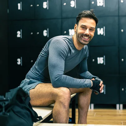 Homme souriant en tenue de sport assis dans un vestiaire avec des casiers numérotés à Salbris en Loir-et-Cher 41
