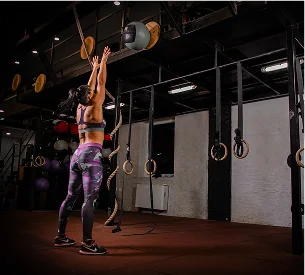 Femme musclée lançant un medecine ball contre un mur dans une salle de sport à Salbris en Loir-et-Cher 41