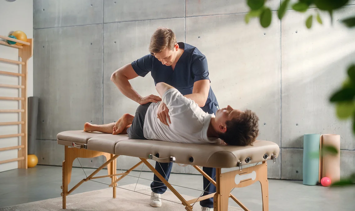 Thérapeute étirant la hanche d'un patient allongé sur une table de massage dans une salle de sport à Salbris en Loir-et-Cher 41